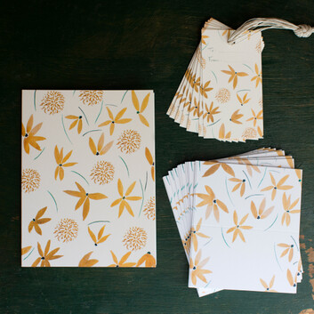 Emily Post Garden Collection by Isal Salazar Gold Floral Greeting Card with gift tags and place cards. A gold water color design of simple petaled flowers and pom pom style flowers across the whole card. This card and set are available through our online shop.